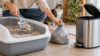 How to dispose of cat litter by scooping used litter into a bag beside a household trash can.
